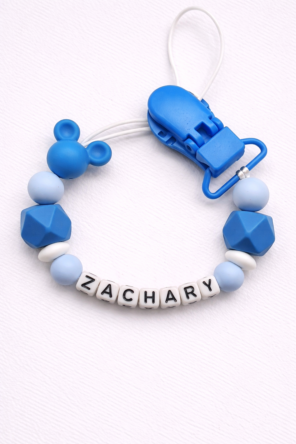 Blue and white dummy clip with 'ZACHARY' on a white background