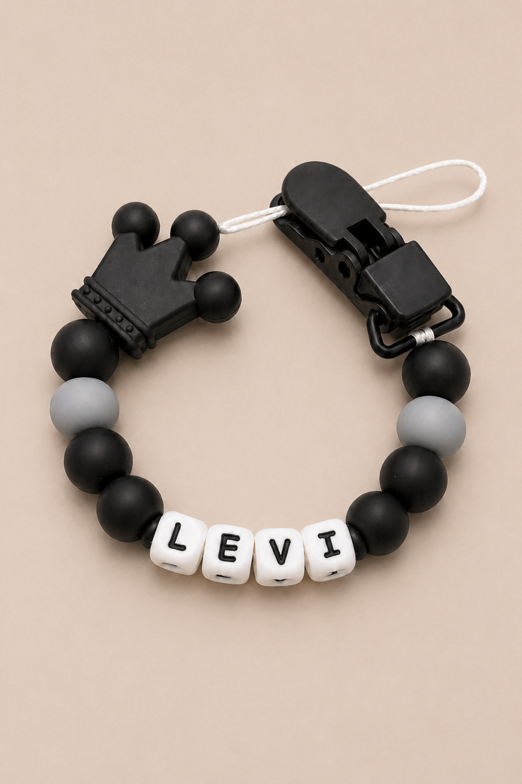 Black and gray beaded bracelet with a name tag on a beige background