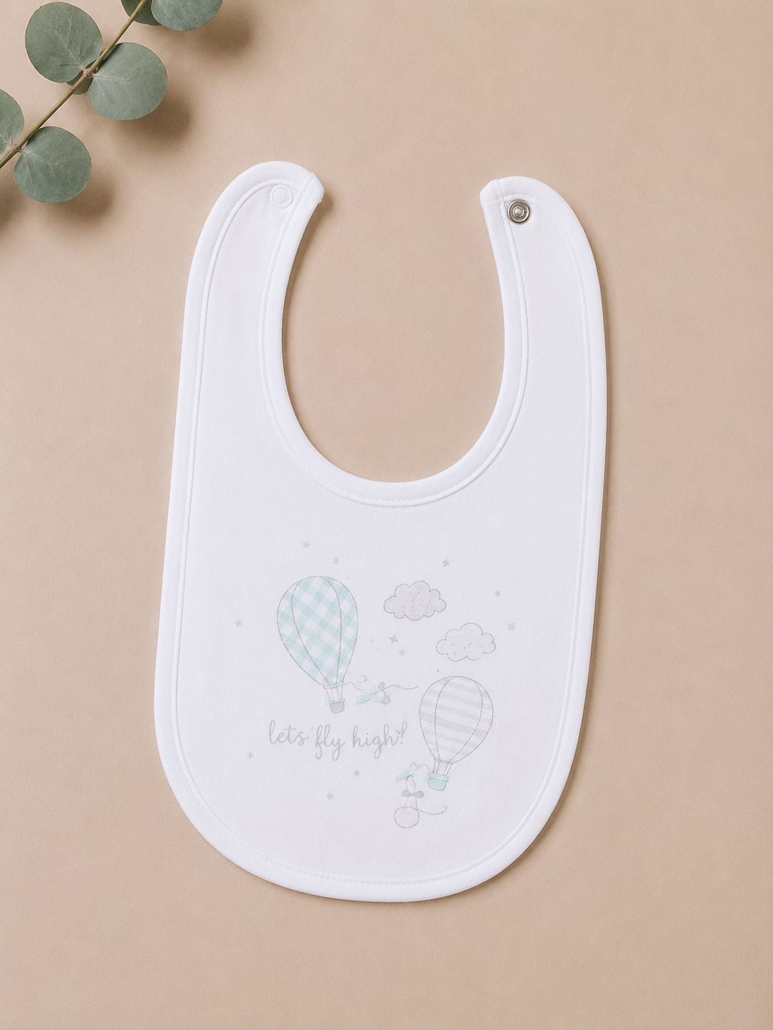 White baby bib with heart and cloud design on a beige background