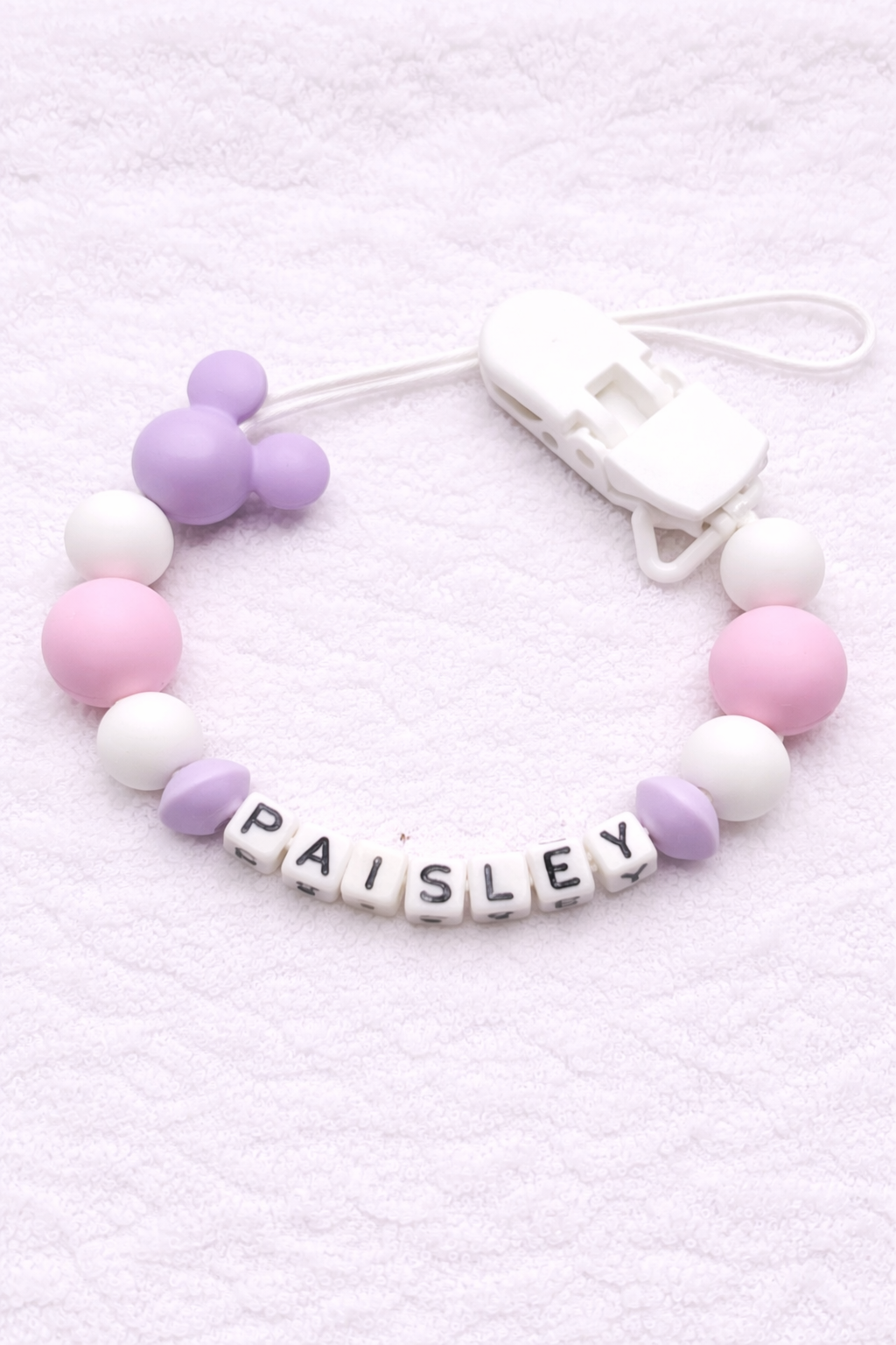 Pacifier clip with pastel-colored beads and a nameplate on a white background
