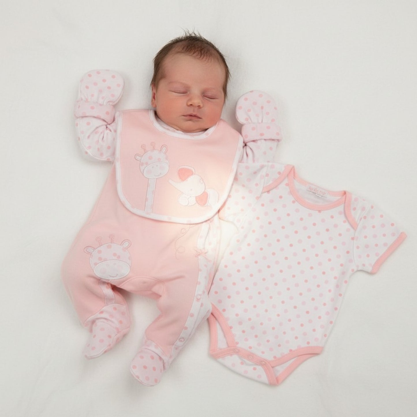Newborn baby in pink babygro with matching outfit on a white background