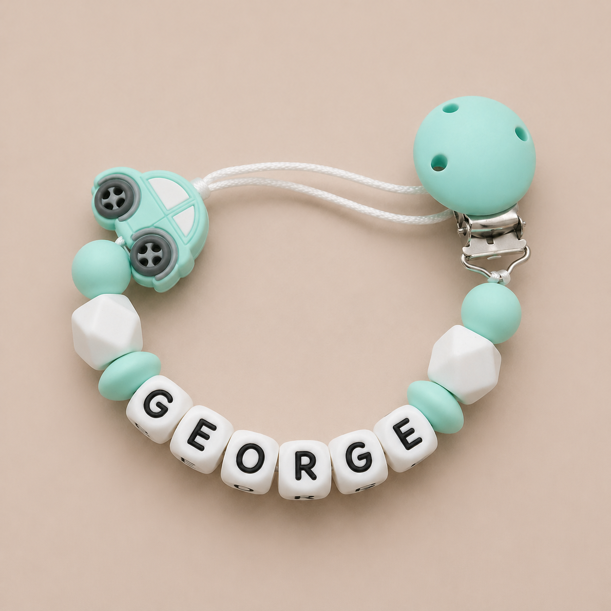 dummy clip with 'GEORGE' beads on a beige background