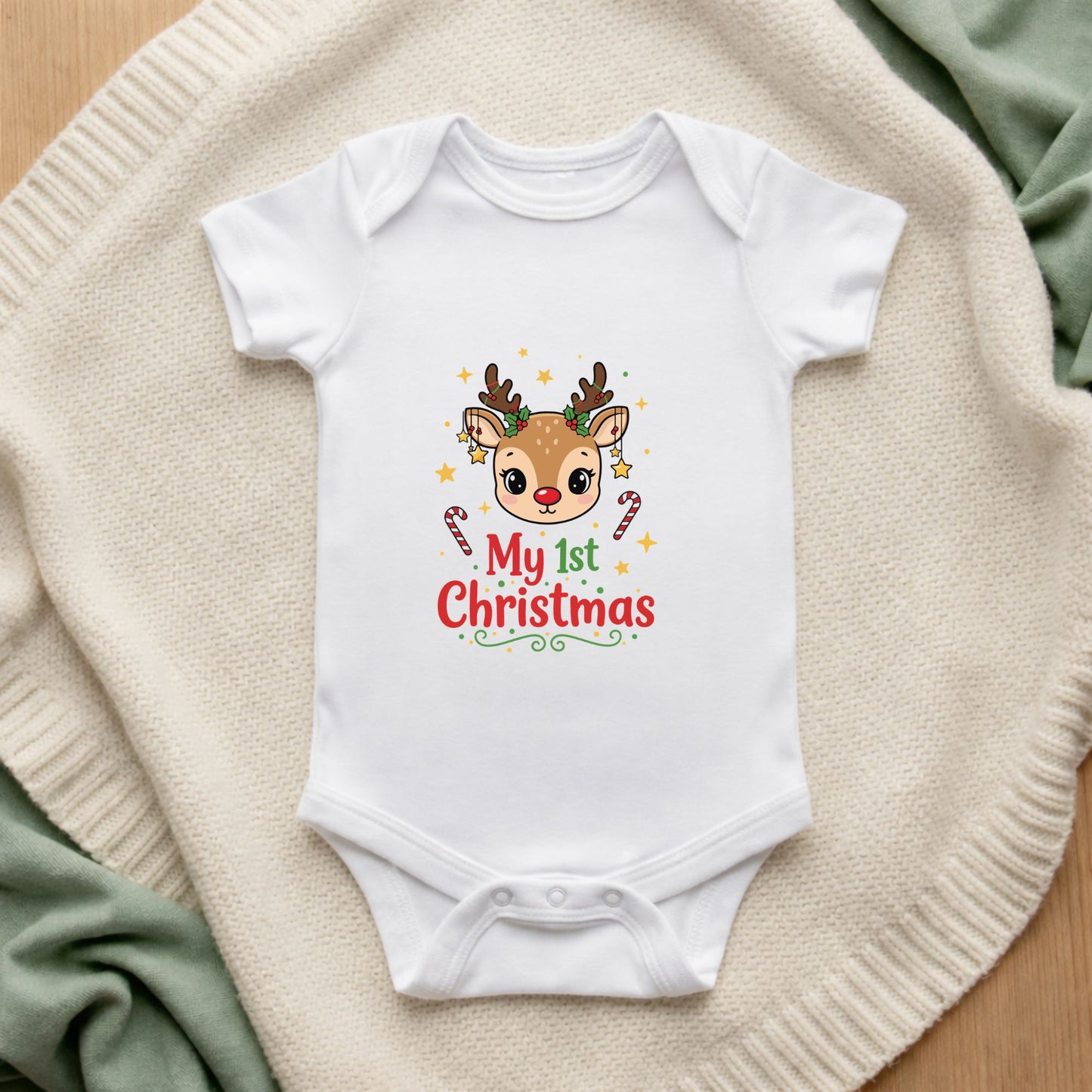 White baby onesie with a reindeer design and 'My 1st Christmas' text on a beige blanket.