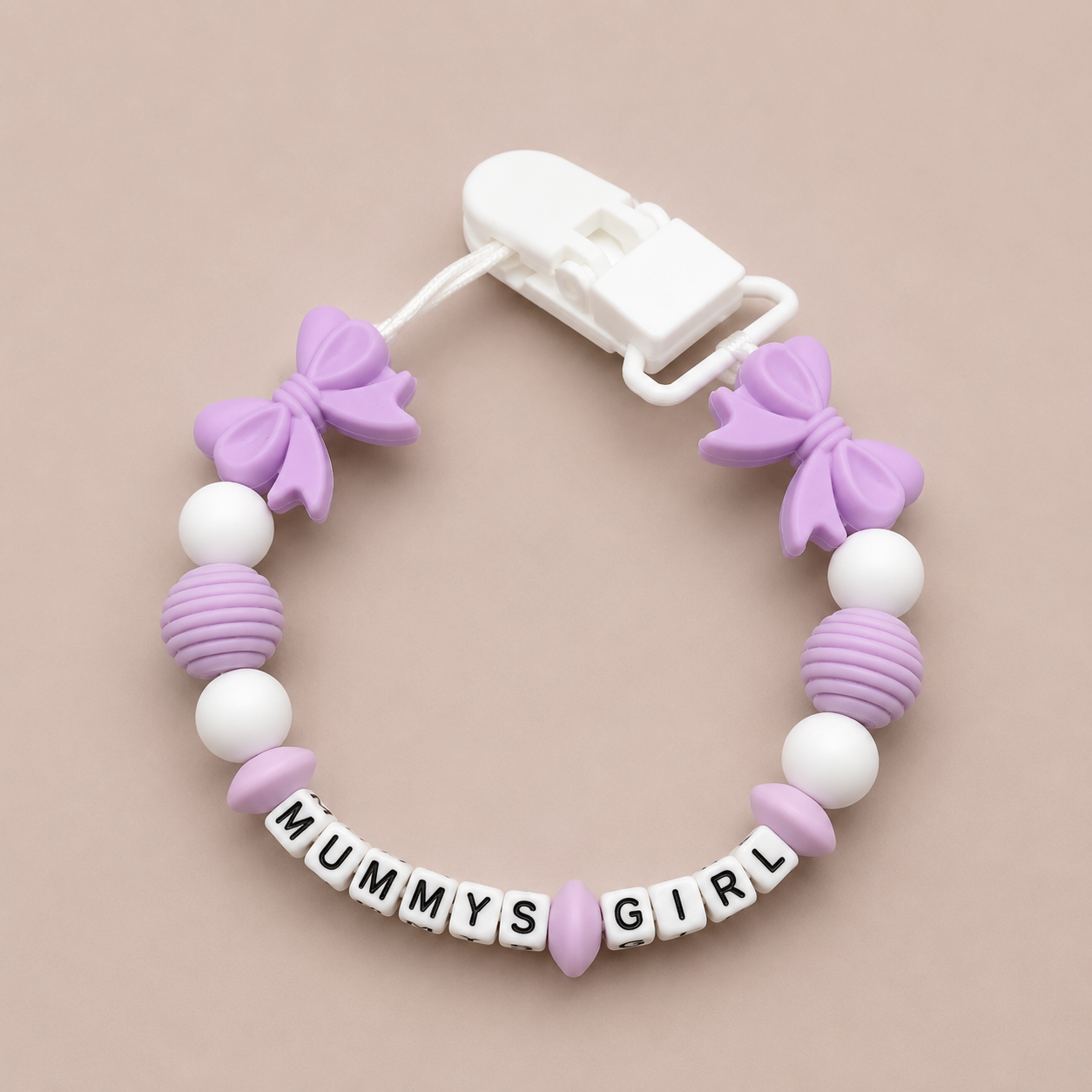 Silicone dummy clip with purple and white beads and 'MUMMYS GIRL' letter beads on a beige background