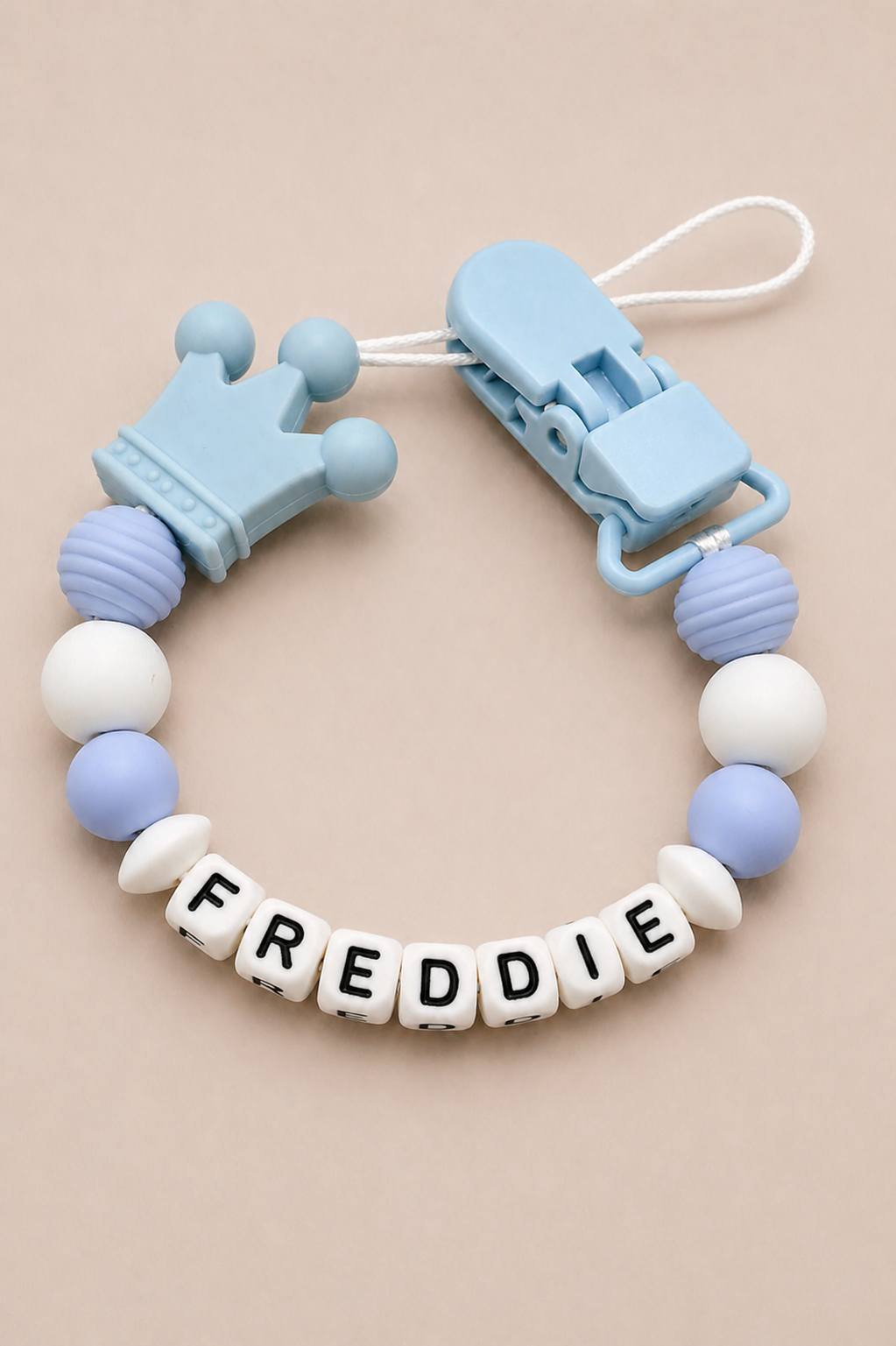 Baby teether with name 'FREDDIE' on a beige background