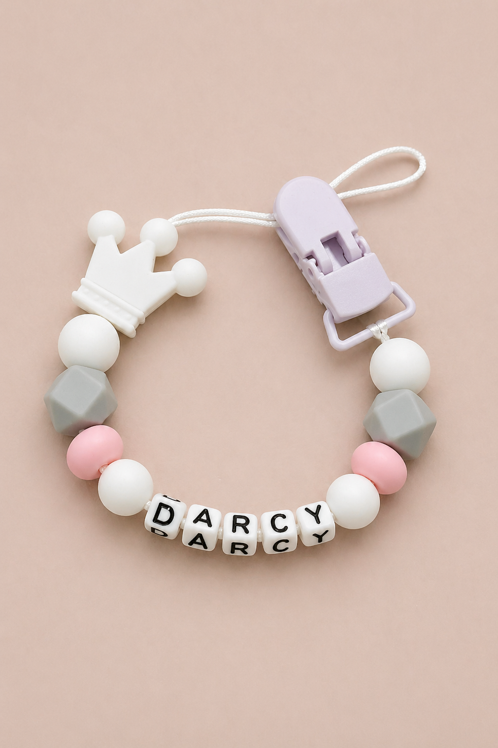 Teething bracelet with geometric beads and a crown charm on a beige background