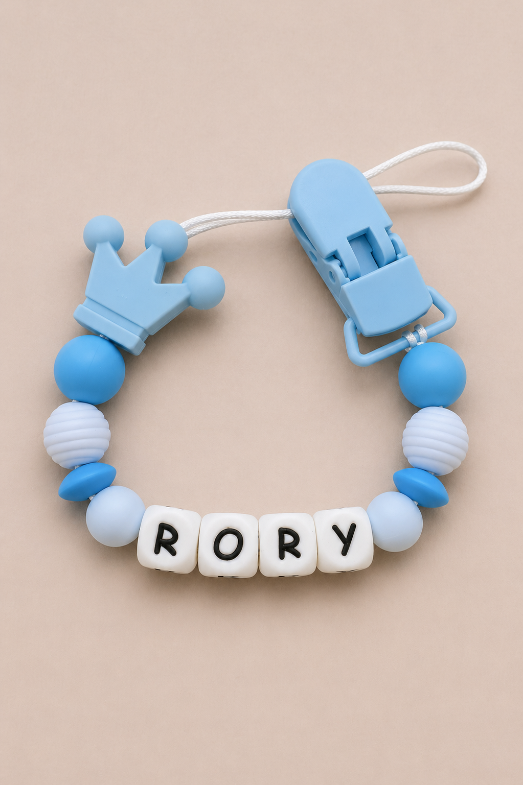 Teething ring with blue and white beads and a clip on a beige background