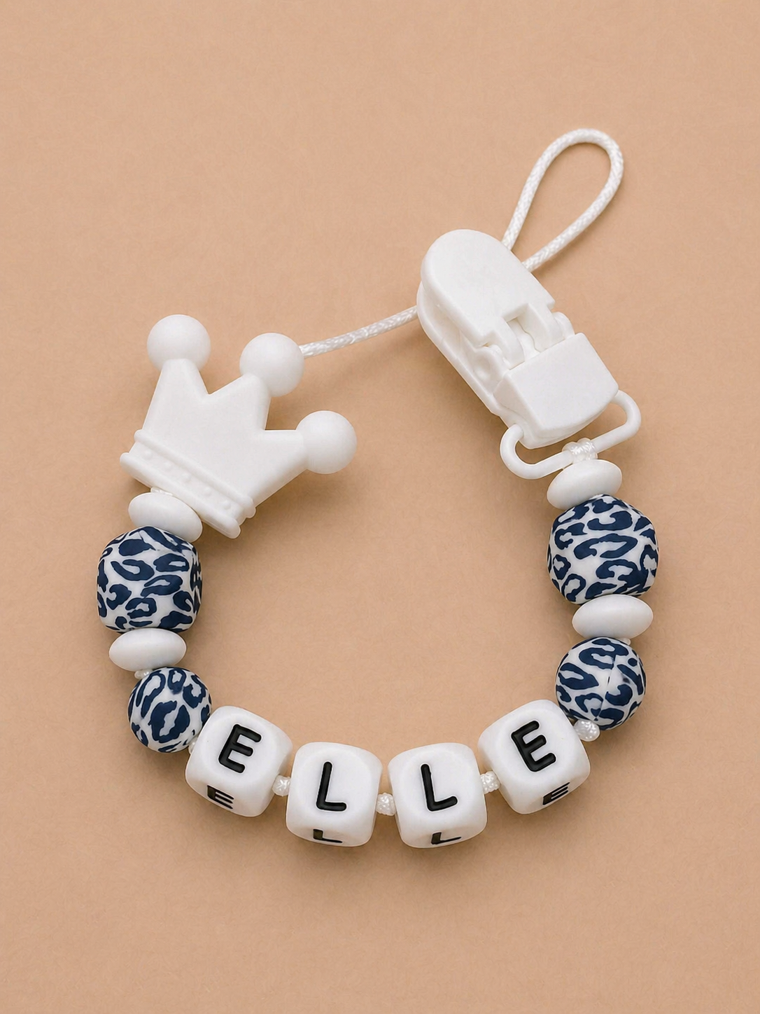 Baby teether with leopard print beads and letter blocks spelling 'ELLE' on a beige background