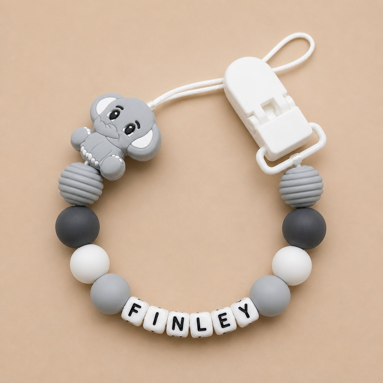 dummy clip with gray elephant design and colorful beads on a beige background