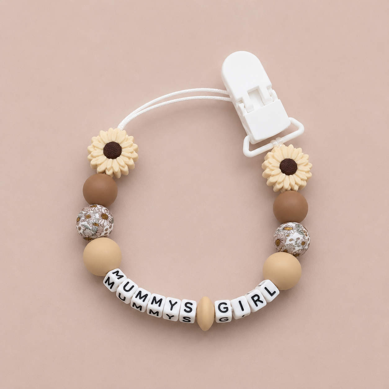 Beaded pacifier clip with 'MUMMY'S GIRL' beads on a beige background