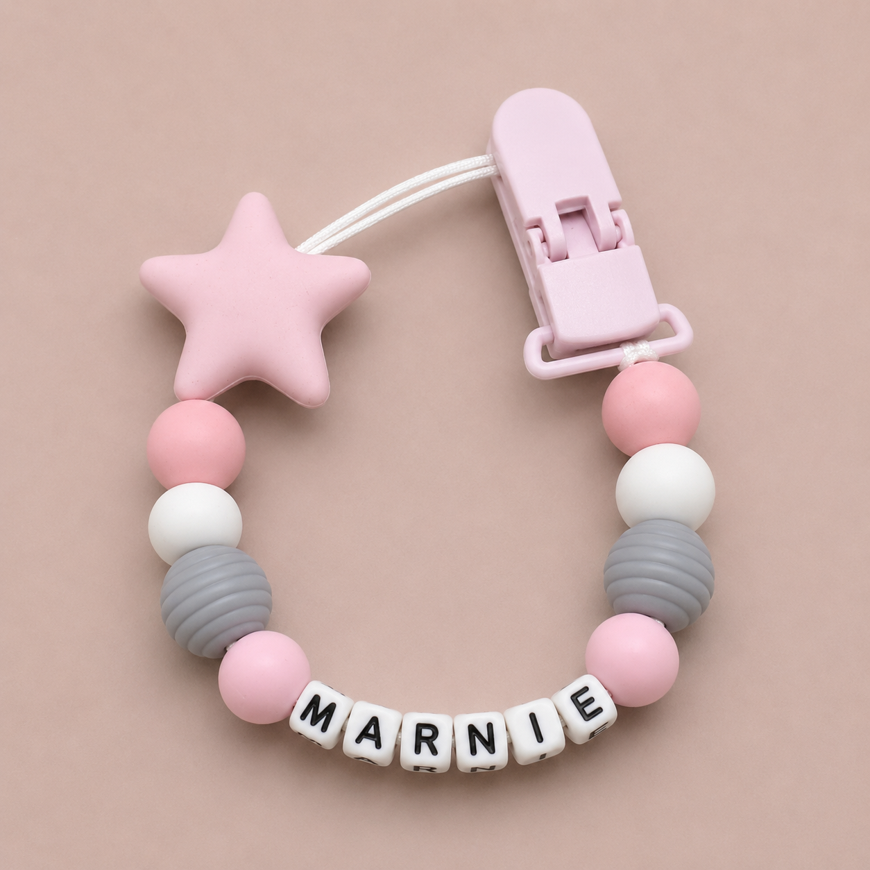 Pink star-shaped dummy clip with a clip and colorful beads on a beige background