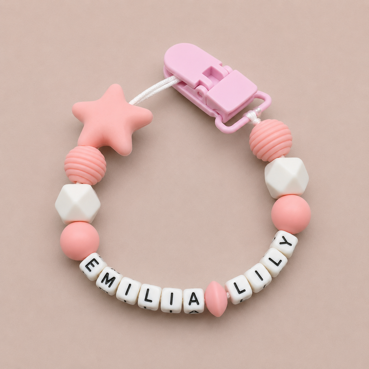 Pink and white dummy clip with name beads on a beige background