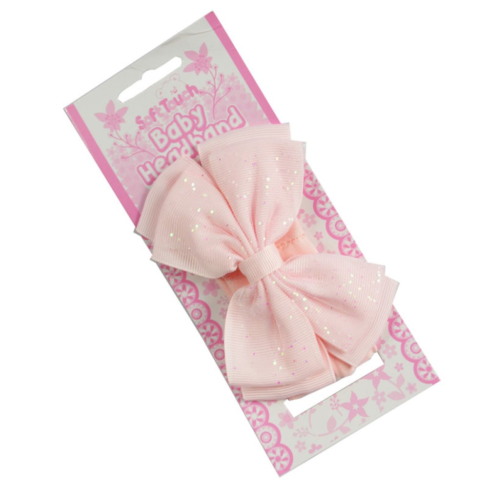 Pink hair bow with polka dots on a decorative pink and white packaging