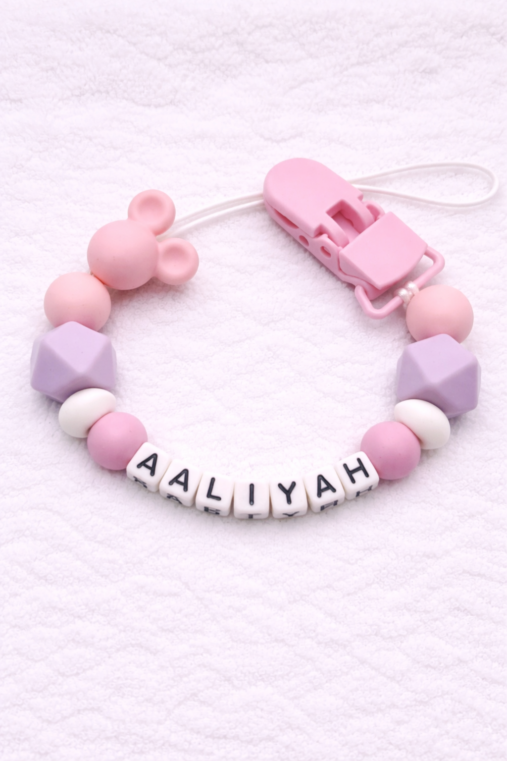 Pastel-colored dummy clip with letter beads spelling 'AALIYAH' on a white background
