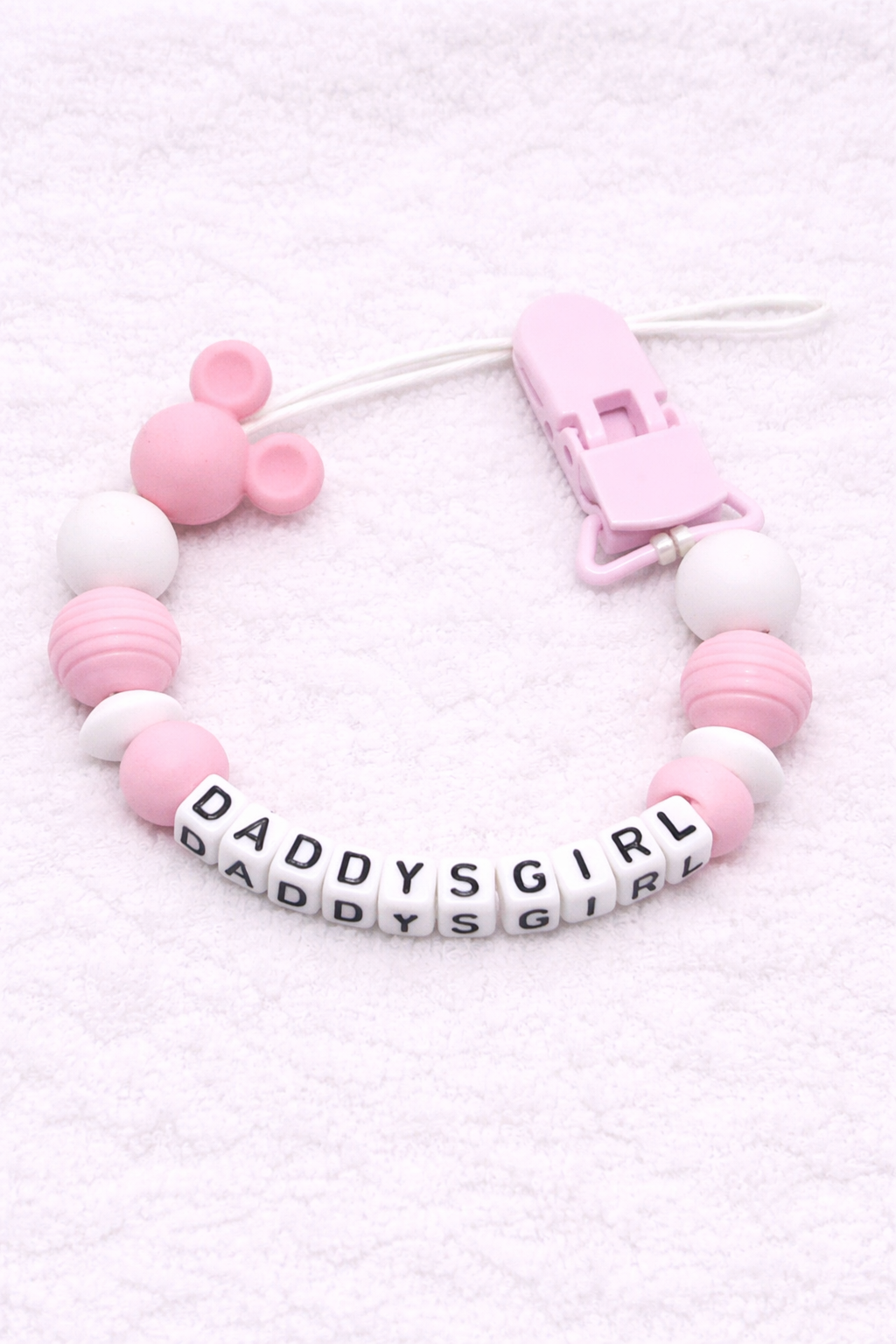 Pink and white teething dummy clip with 'DADDYS GIRL' beads on a light pink background