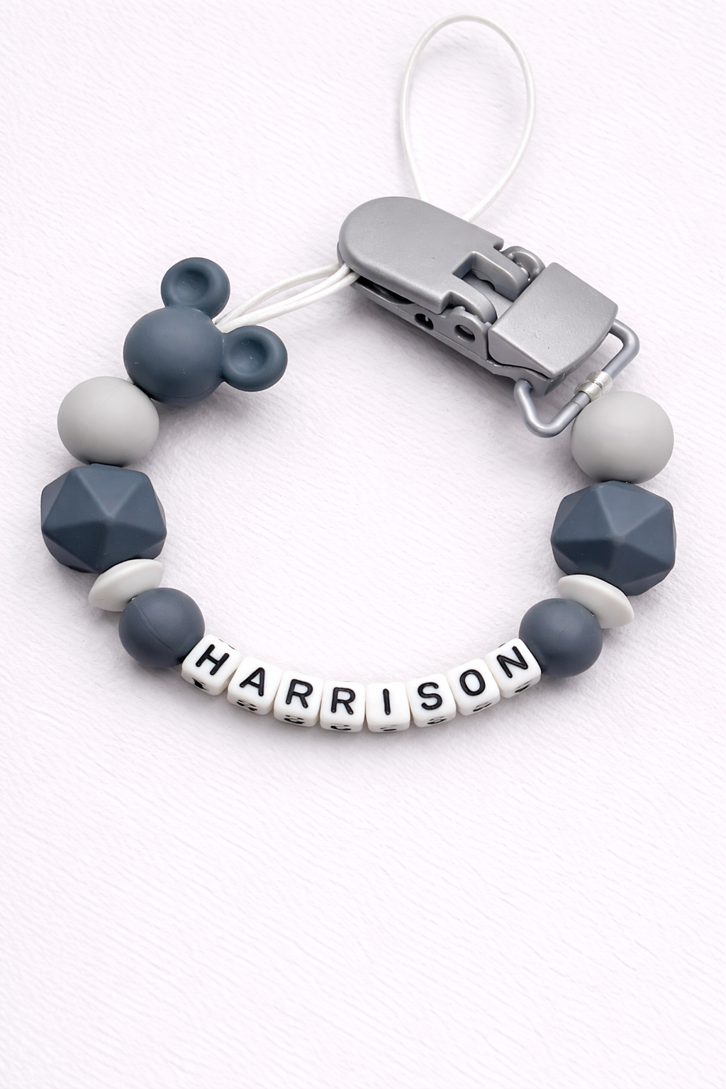 Beaded pacifier clip with 'HARRISON' on a white background