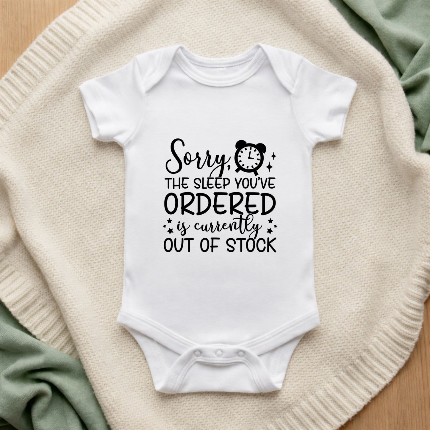 White baby onesie with humorous text on a textured surface Sorry The Sleep You've Ordered Is Currently Out Of Stock Baby Bodysuit