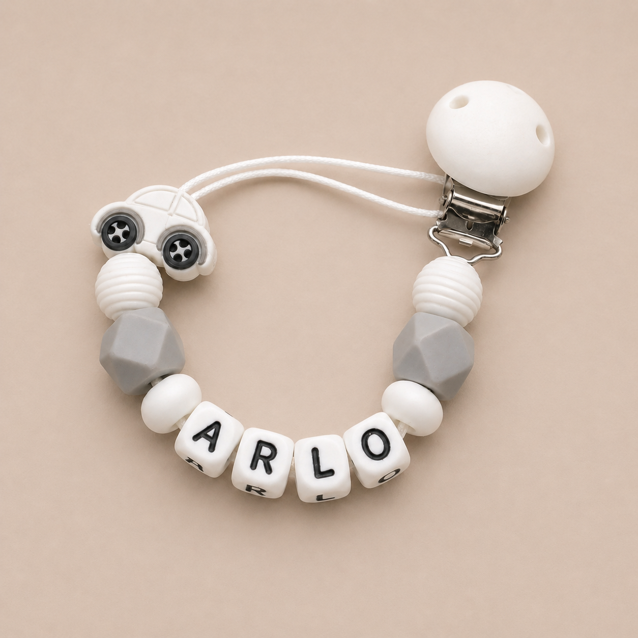 dummy clip with letter beads spelling 'ARLO' on a beige background