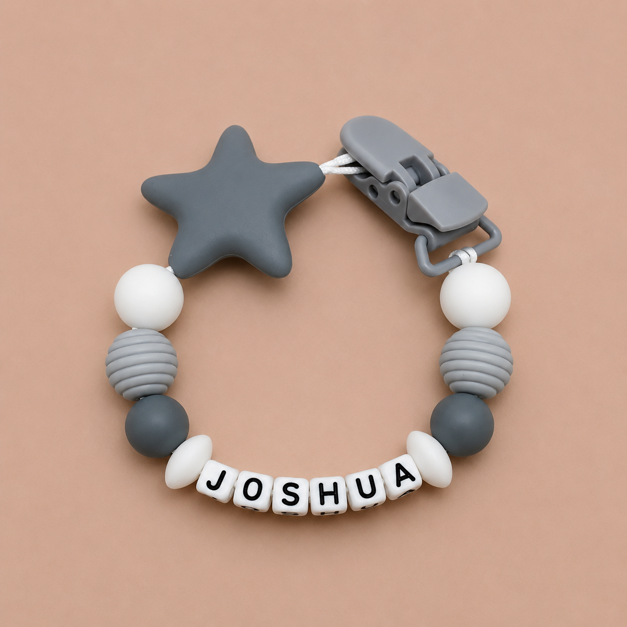 dummy clip with star-shaped clip and 'JOSHUA' name on a beige background