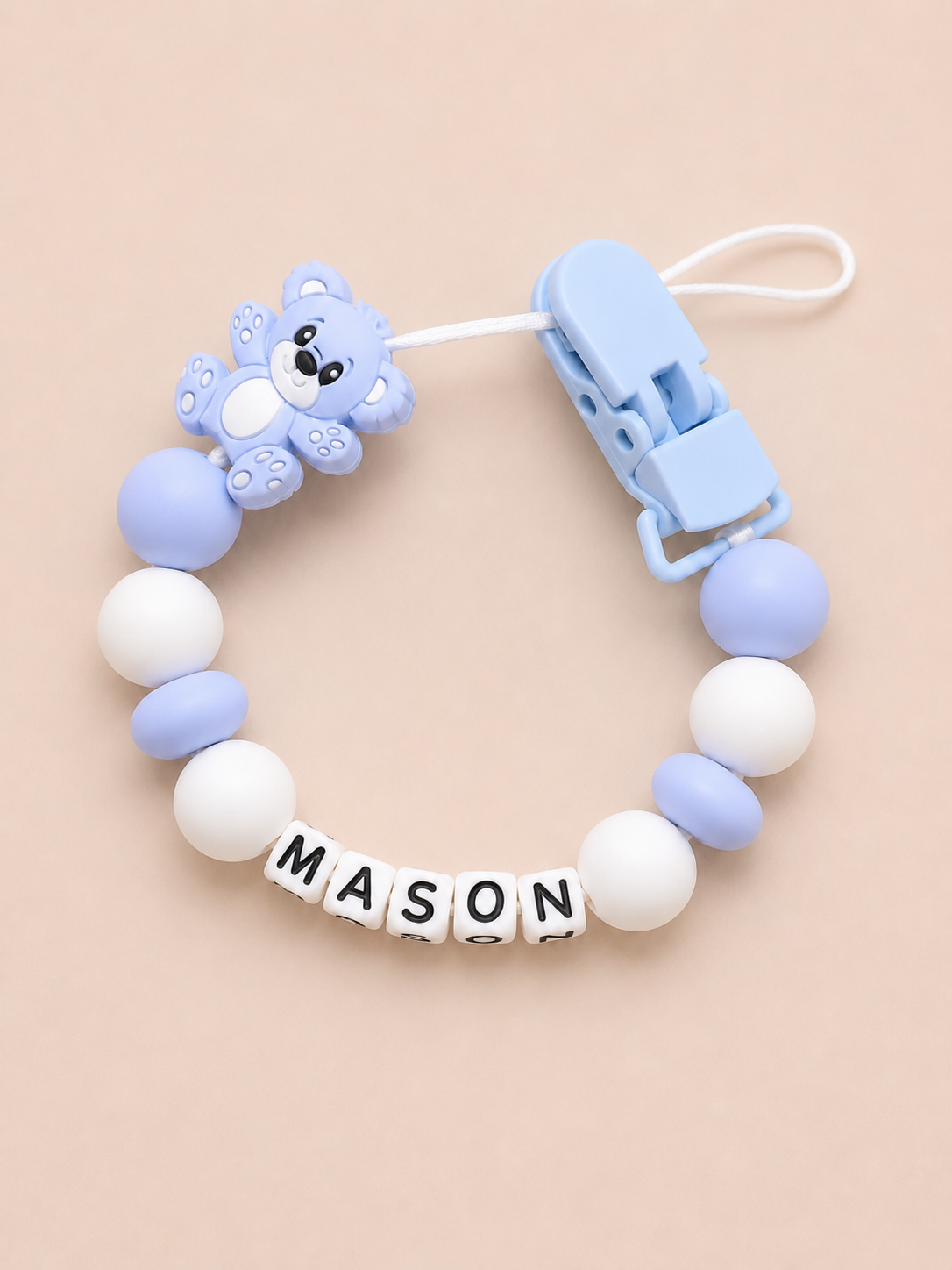 Baby dummy clip with name 'MASON' on a beige background