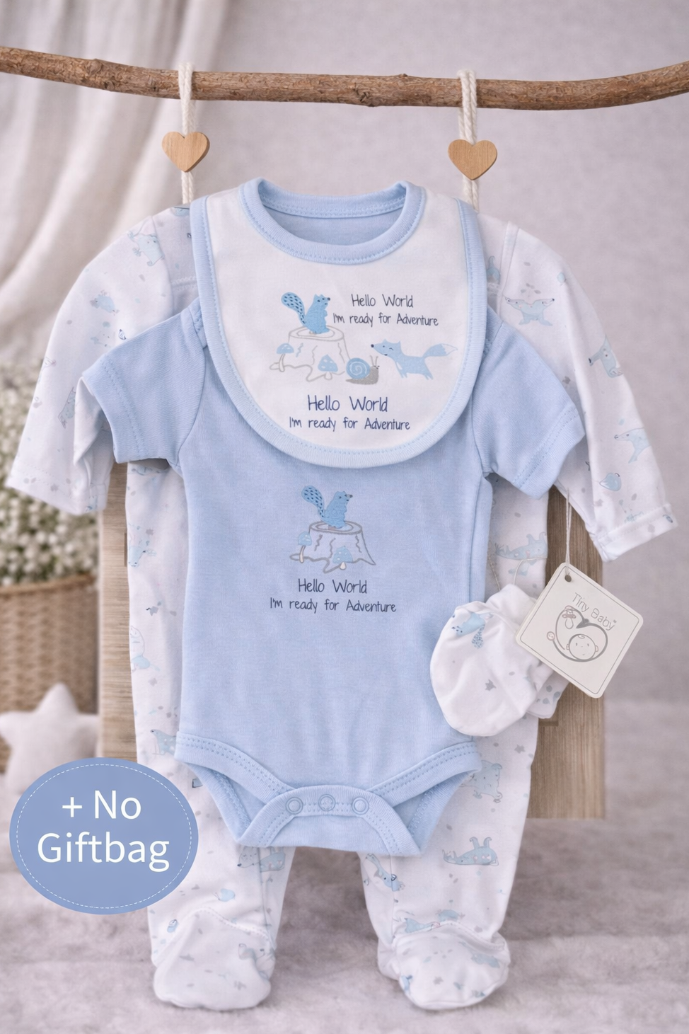 Baby boy clothing set with bib, onesie, and socks on a wooden branch.