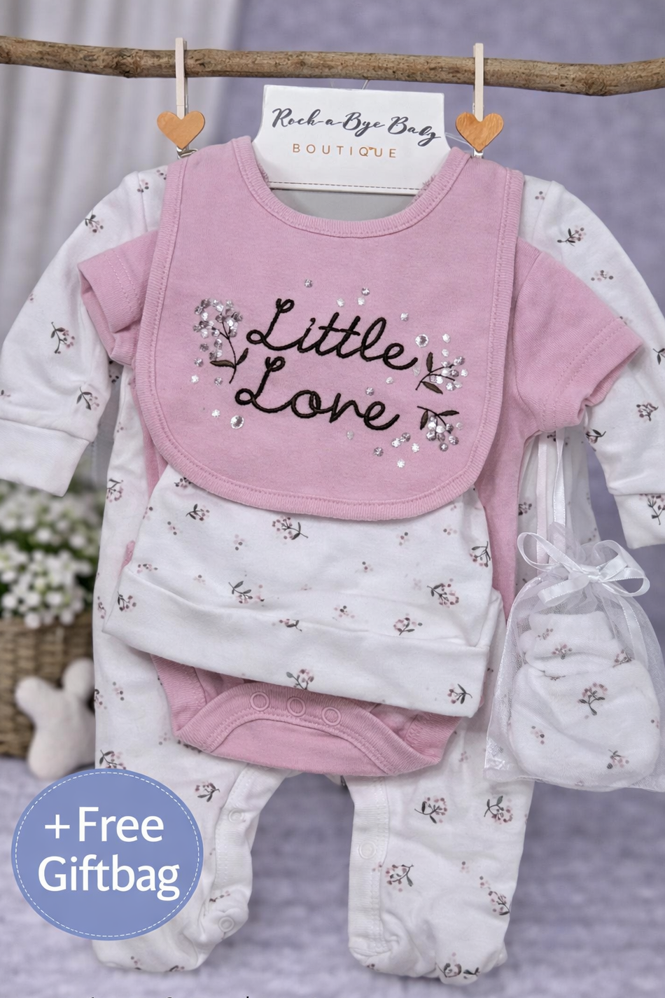 Baby gift set with pink bib, white shirt, and pants on a gray background