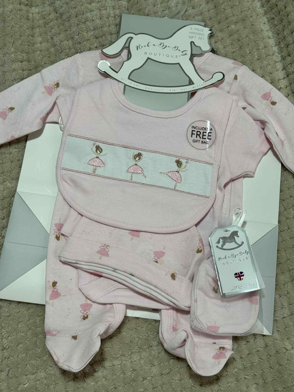 Pink baby outfit set with matching bib on a gray surface