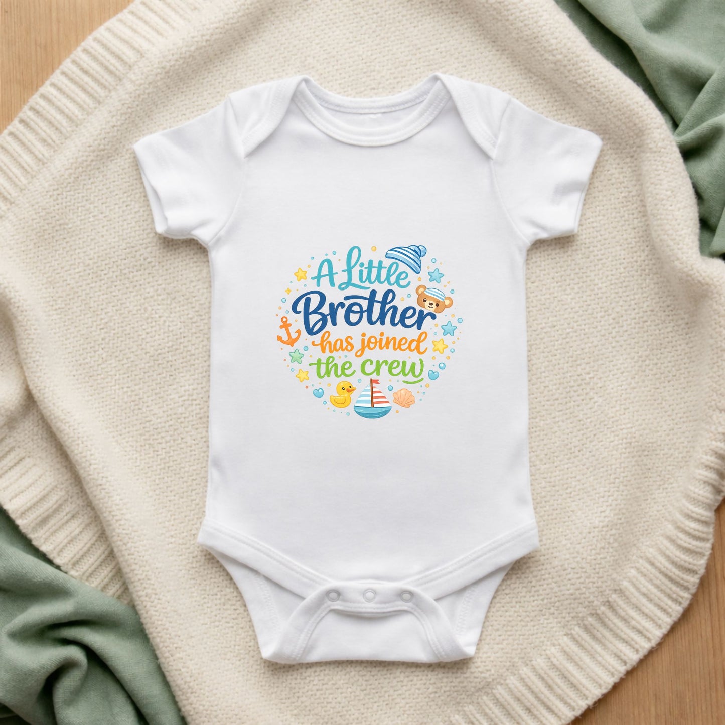 White baby onesie with colorful text on a textured surface A Little Brother Has Joined the Crew Baby Bodysuit