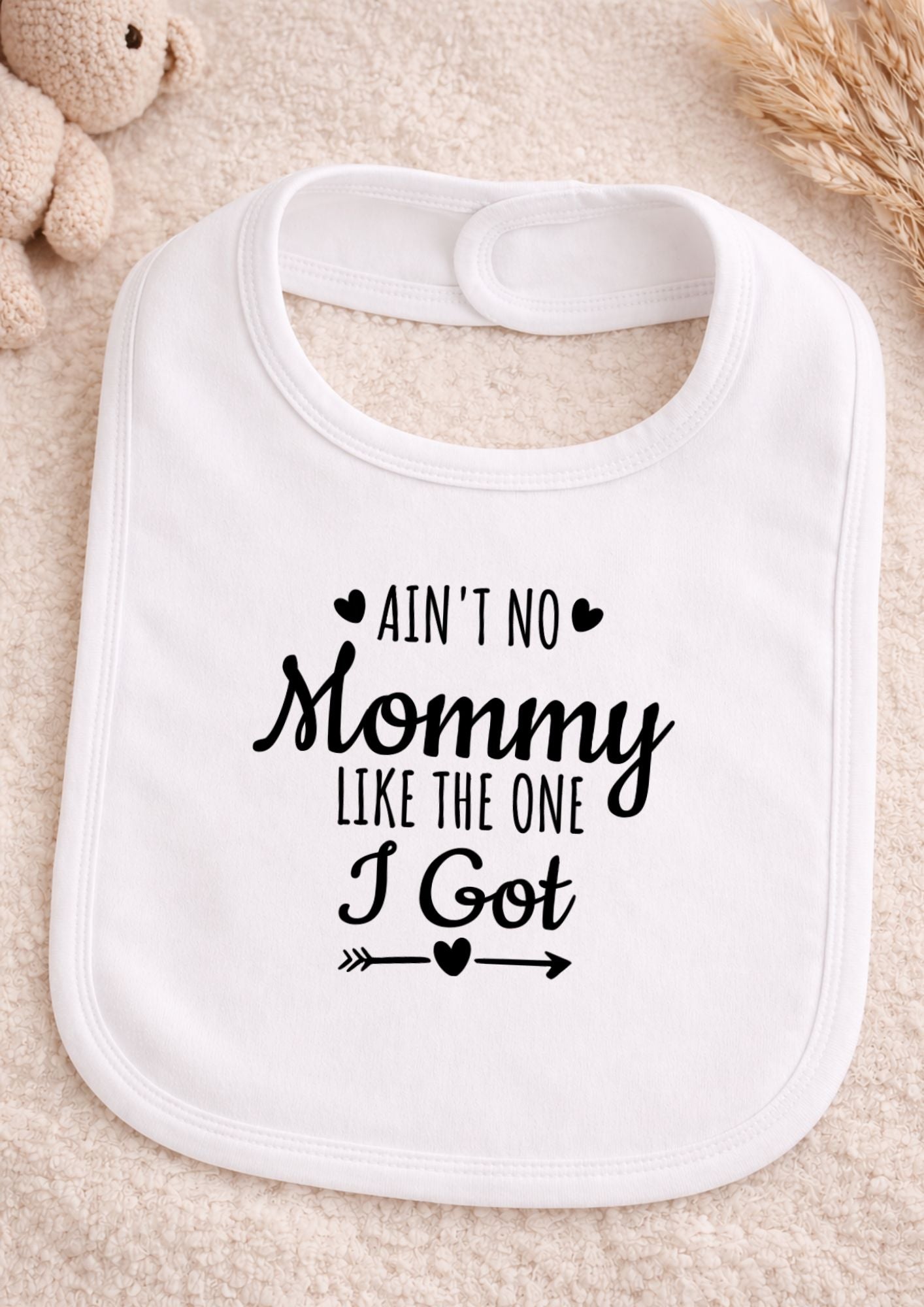 White baby bib with text on a beige surface Ain't No Mommy Like The One I Got Baby Bib | Funny Newborn Gift