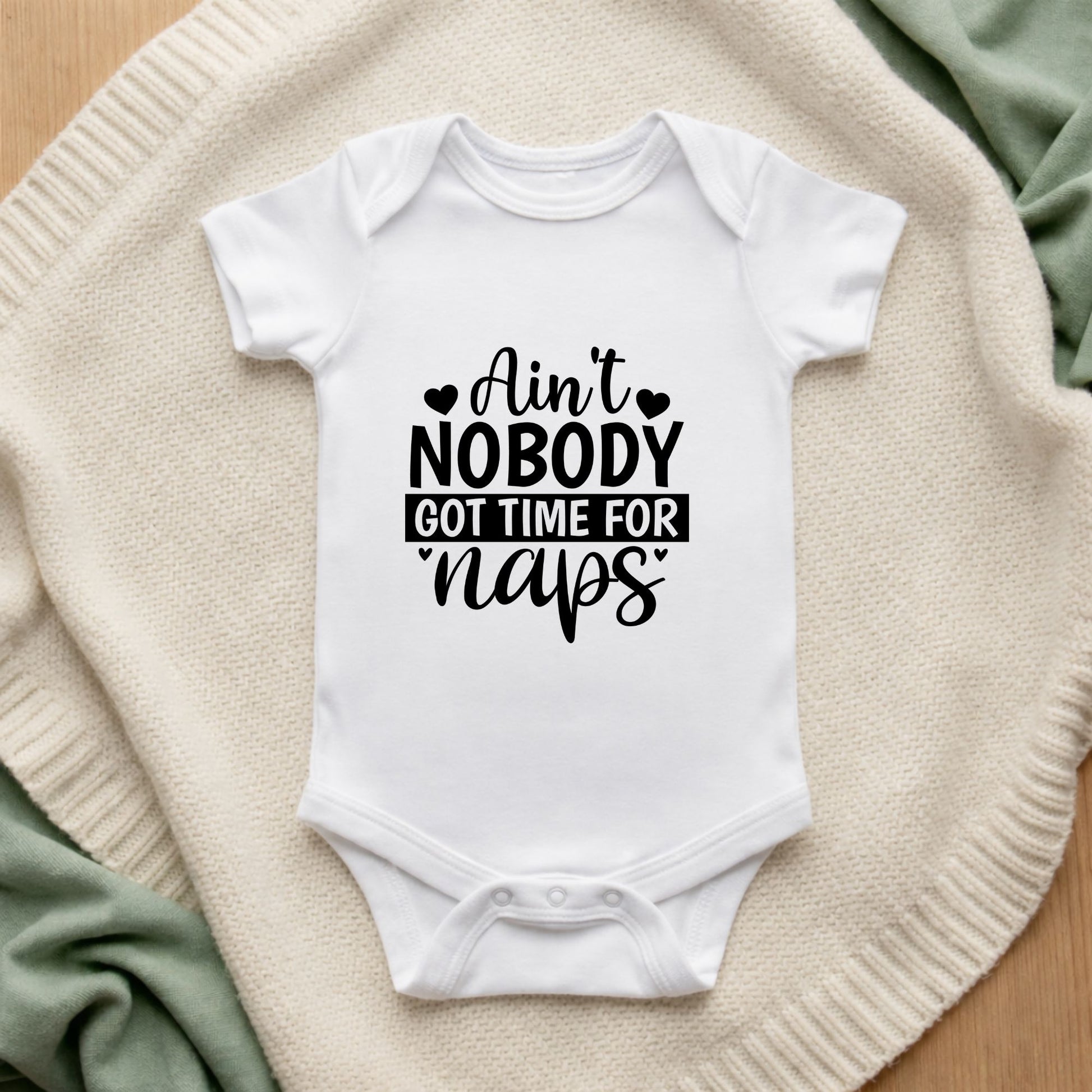 White baby onesie with humorous text on a textured surface Ain't Nobody Got Time For Naps Baby Bodysuit