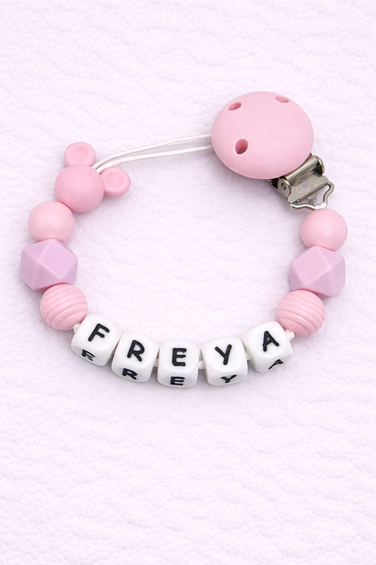 Pink beaded dummy clip with 'FREYA' on a light pink background