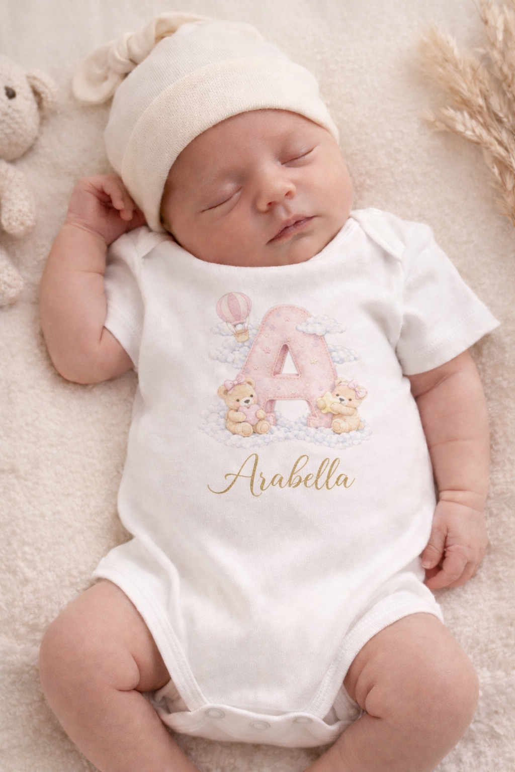 Newborn baby wearing a white onesie with a personalized design and name.