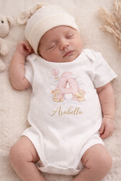 Newborn baby wearing a white onesie with a personalized design and name.