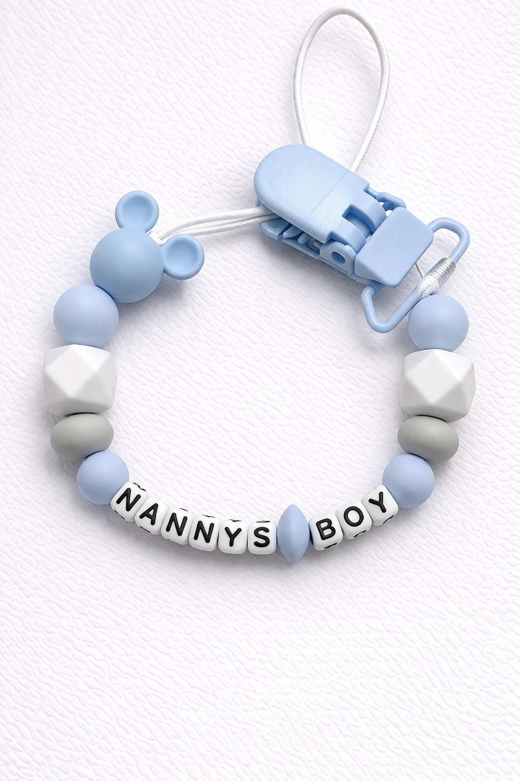 Baby dummy clip with 'NANNY'S BOY' beads on a white background