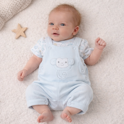Baby wearing a light blue romper with bear design on a soft surface