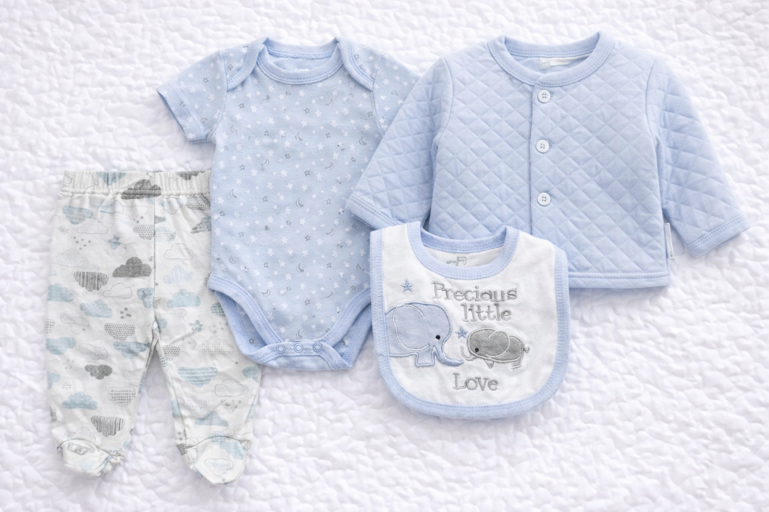 Baby boys four-piece outfit set featuring a light blue quilted jacket without collar, matching star-print bodysuit, cloud-pattern trousers, and coordinating bib. Soft, baby-friendly fabrics ideal for everyday wear, newborn outfits, and gifting.