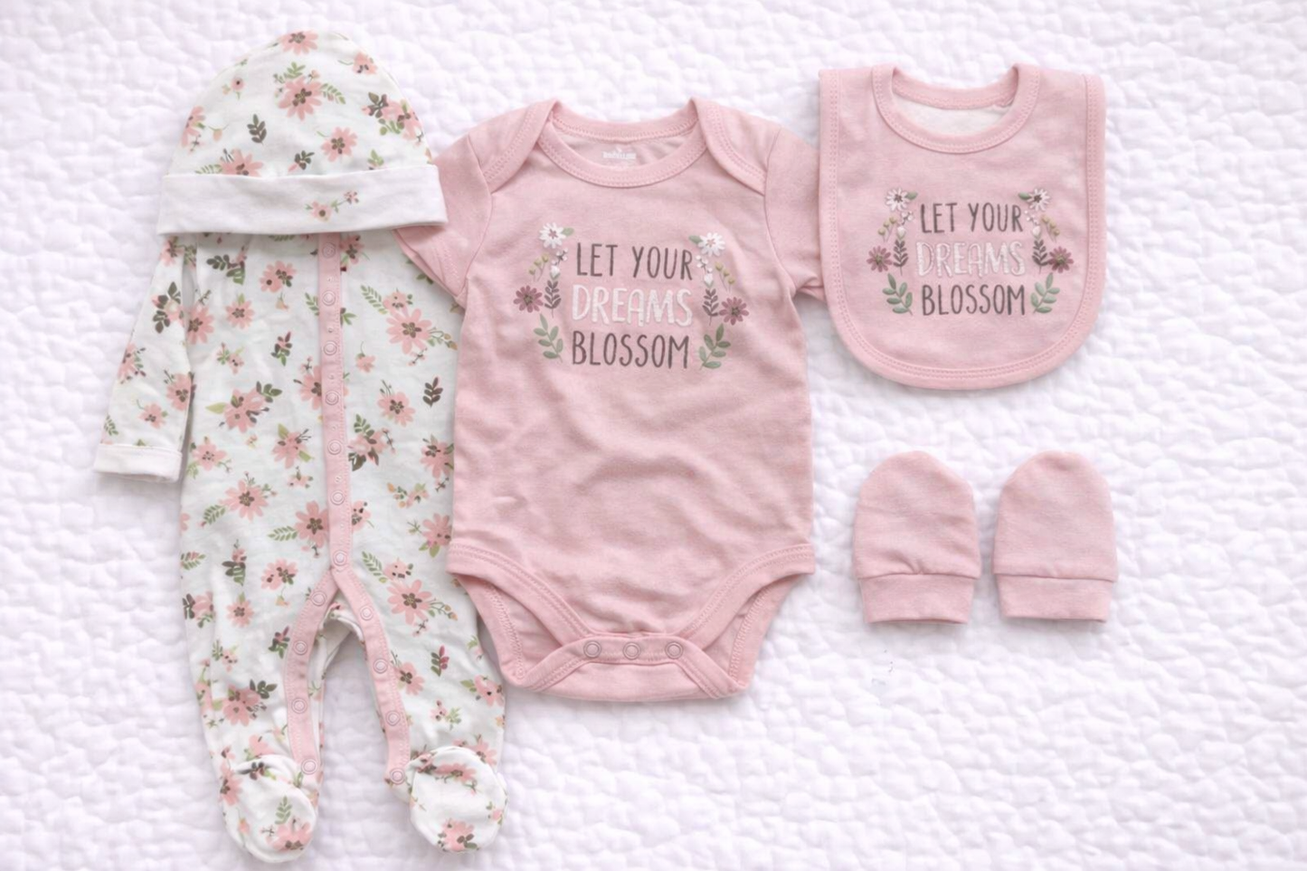Pink baby girl 5 piece matching outfit set featuring a floral babygrow, short sleeve bodysuit with “Let Your Dreams Blossom” print, coordinating bib, hat and mittens. Soft cotton newborn gift set ideal for baby showers and everyday wear.