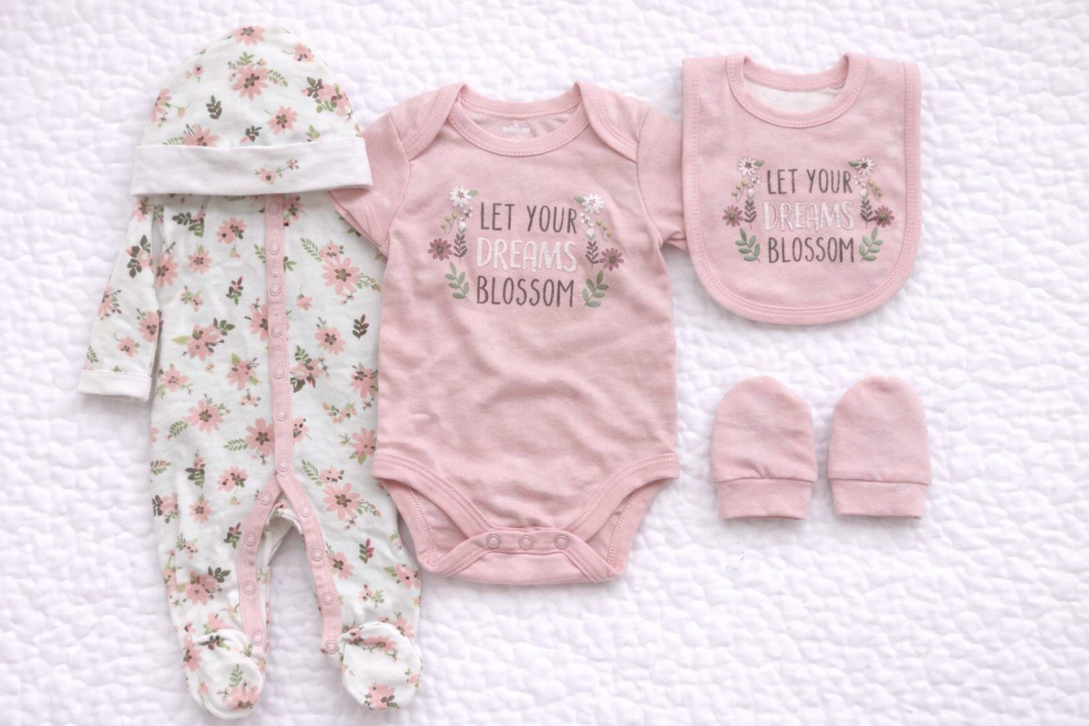 Pink baby girl 5 piece matching outfit set featuring a floral babygrow, short sleeve bodysuit with “Let Your Dreams Blossom” print, coordinating bib, hat and mittens. Soft cotton newborn gift set ideal for baby showers and everyday wear.