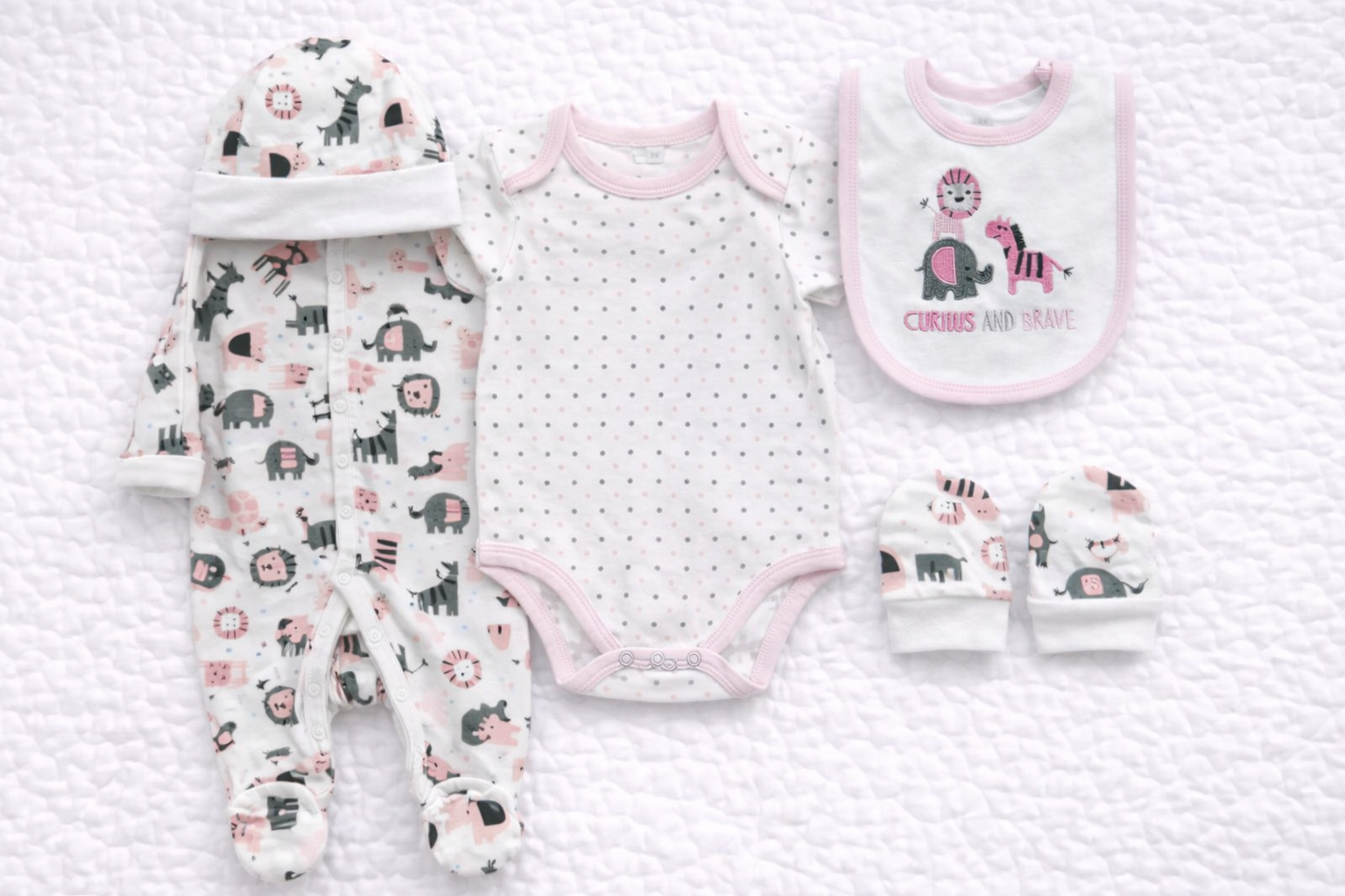 Five-piece baby girl outfit set featuring a matching jungle animal print babygrow, short-sleeve bodysuit, soft hat, coordinating mittens, and embroidered bib. Designed in soft pink, grey, and white tones with playful animal designs, perfect for newborn comfort, everyday wear, or baby shower gifts.