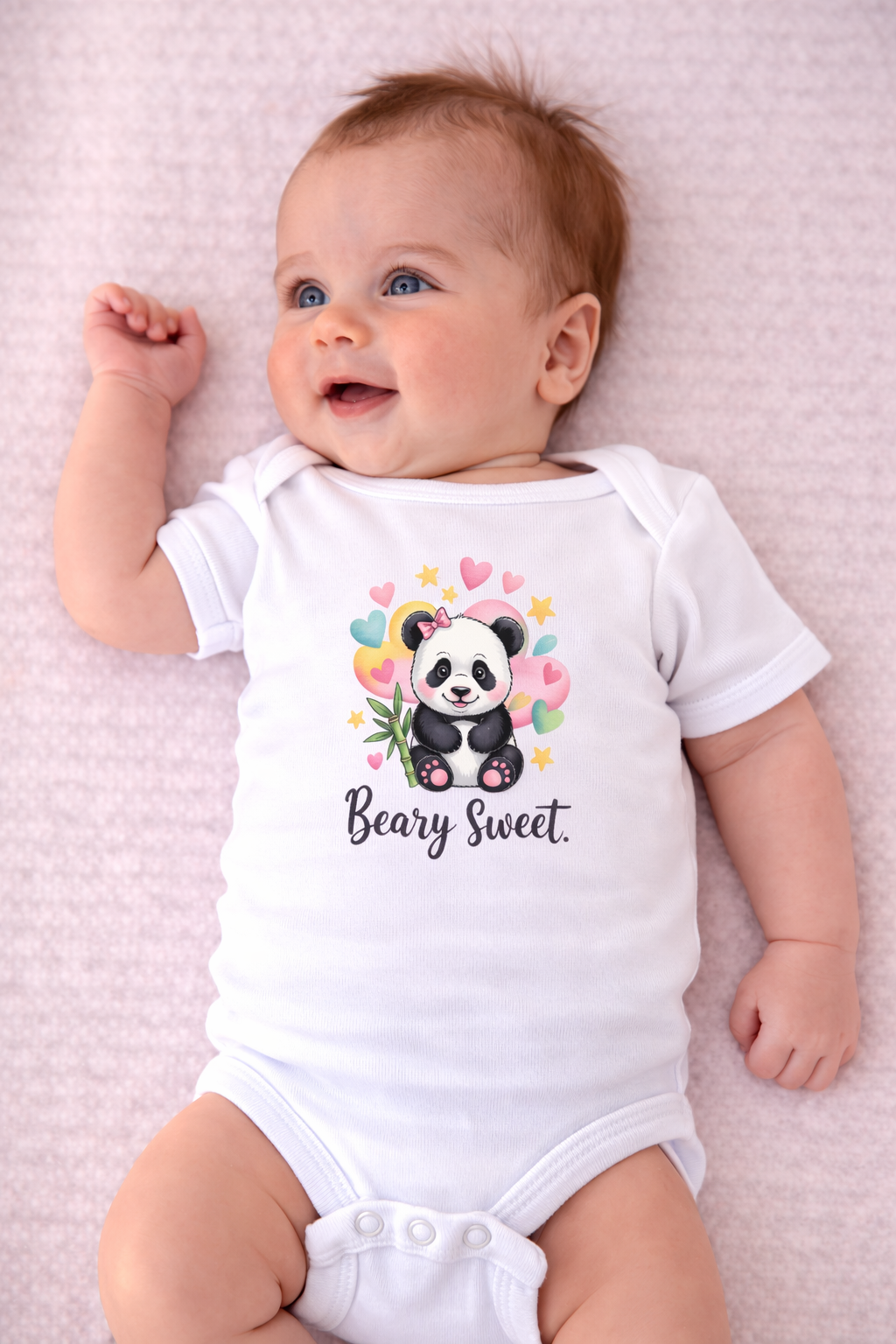 Baby wearing a white onesie with a panda design and 'Beary Sweet' text on a pink blanket.