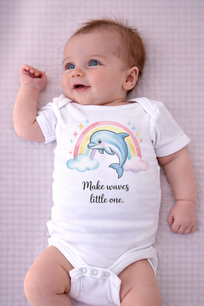 Baby wearing a onesie with a dolphin and rainbow design on a pink checkered background