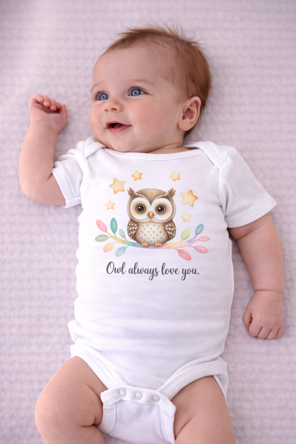 Baby wearing a onesie with an owl design and text on a light purple textured background