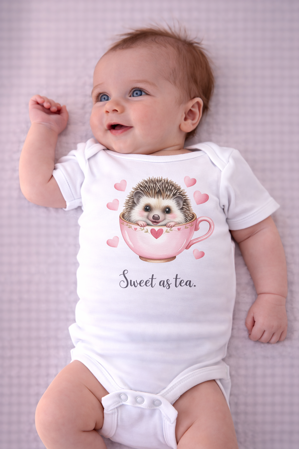 Baby wearing a onesie with a hedgehog design and text on a light purple background