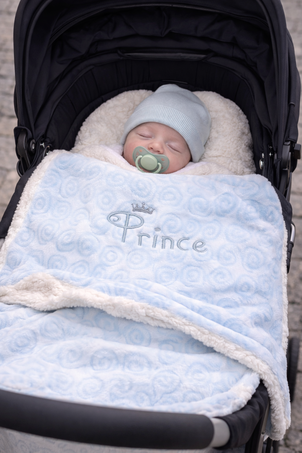 Soft cable knit baby wrap featuring a swirl design with a plush sherpa backing, perfect for keeping newborns warm and comfortable. Ideal for pram use, cuddles, and cosy naps