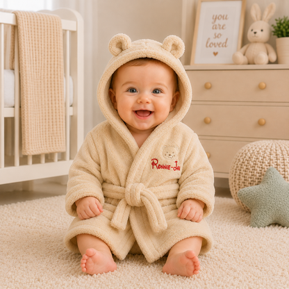 Baby in a beige robe with bear ears in a nursery setting