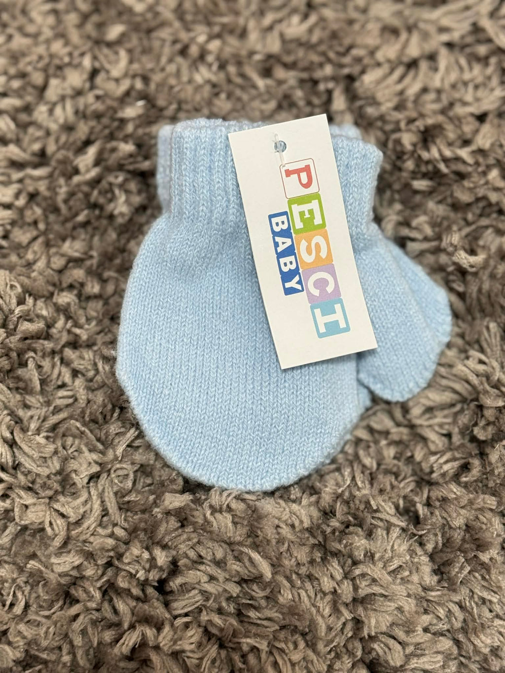 Light blue baby bootie with a colorful label on a brown textured surface