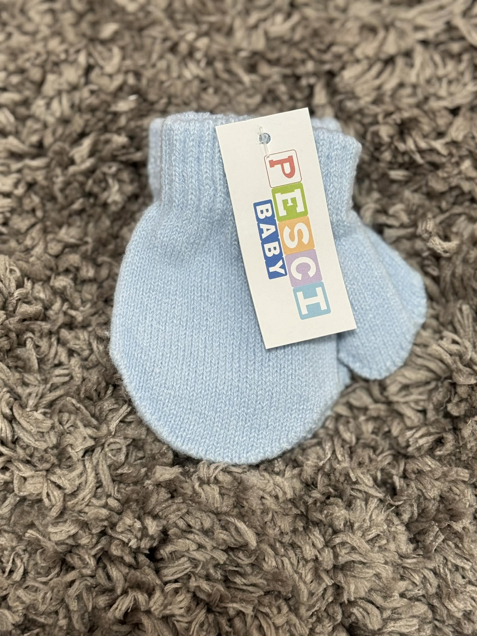 Light blue baby bootie with a colorful label on a brown textured surface