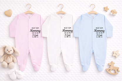 Three baby footed sleepsuits in pink, white and light blue displayed side by side on a white quilted background, each featuring the slogan “Ain’t No Mommy Like The One I Got” in black text, styled as a personalised baby gift mockup.