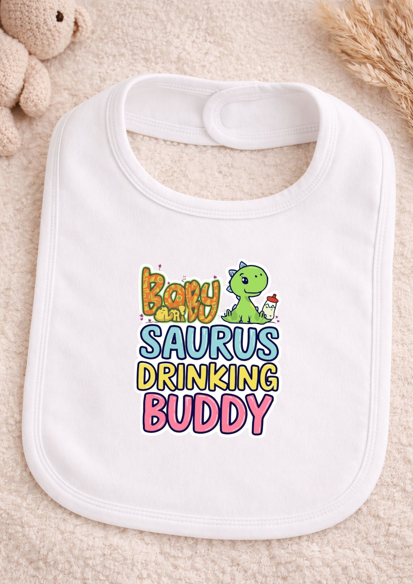White bib with colorful text and dinosaur graphic on a beige surface