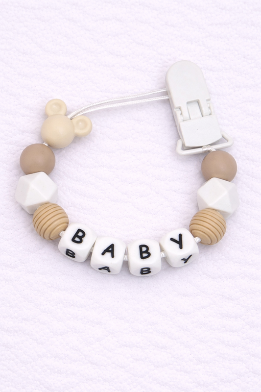 Baby dummy clip with letter beads spelling 'BABY' on a light purple background